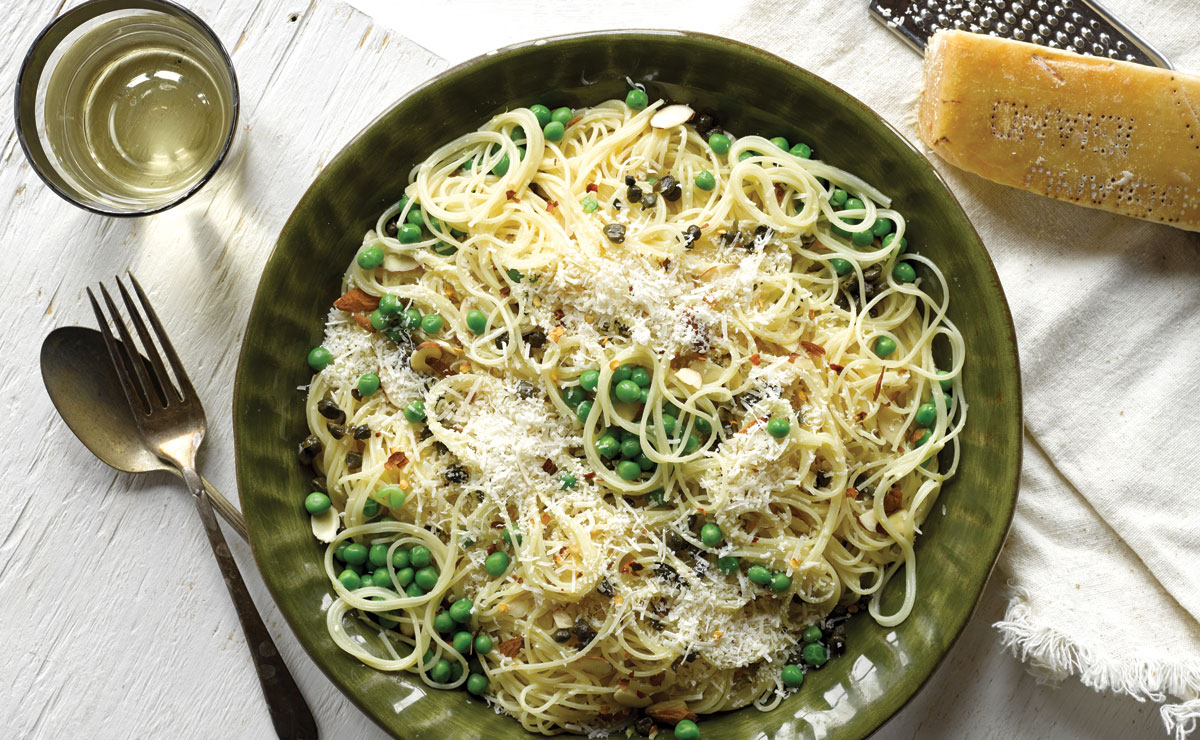 a large plate filled with spaghetti and peas topped with parmesan