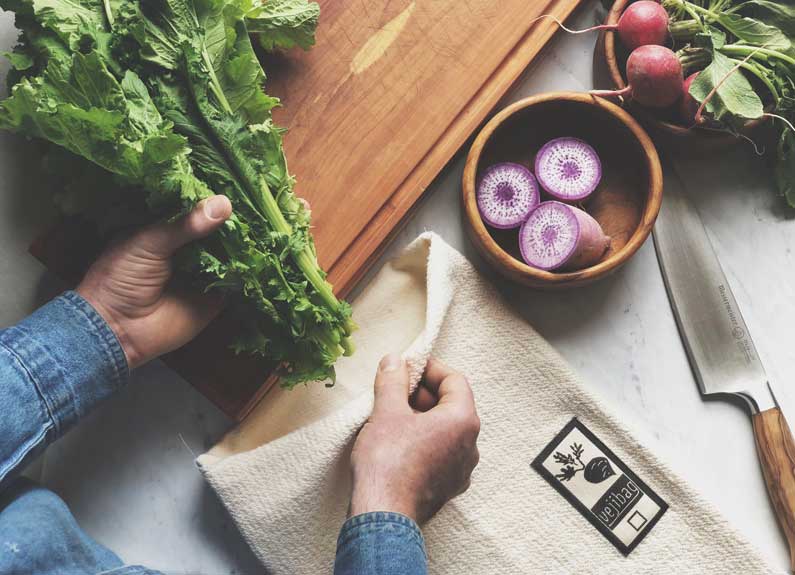 a person putting lettuce into a reusable produce bag