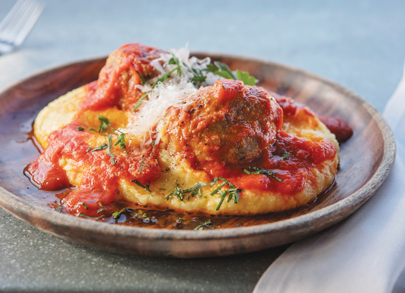 a plate of polenta with meatballs and tomato sauce