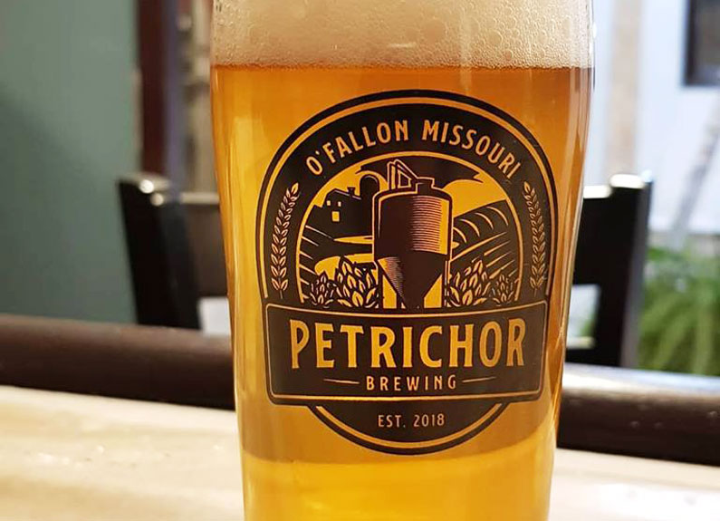 a glass of beer with the petrichor brewing logo