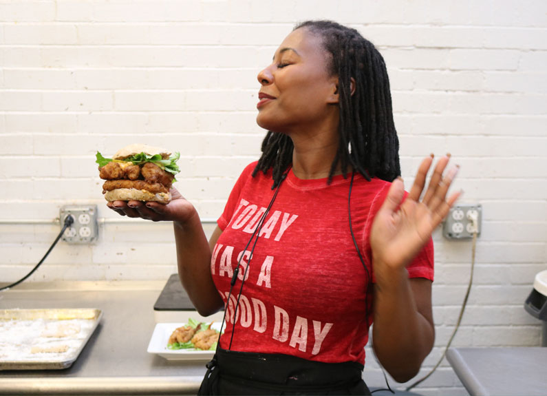 a woman in a red t-shirt posing with a faux fish sandwich