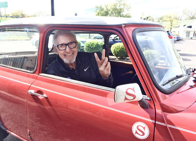 a bearded man sitting in a red mini cooper