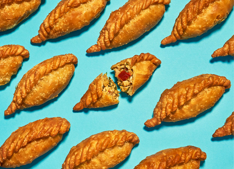 several empanadas lined up diagonally on a blue background