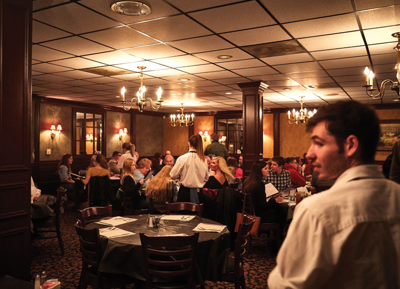 a busy, dimly lit dining room with white tablecloths