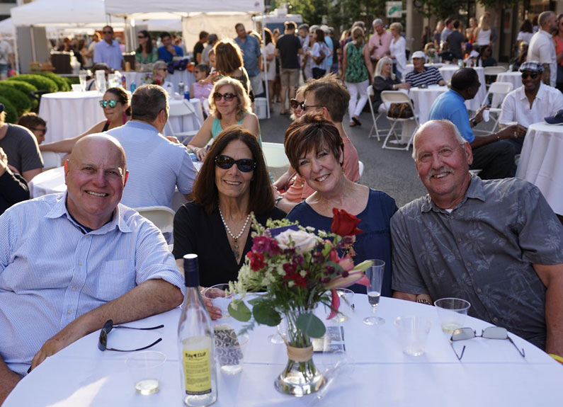 four people sitting a table with a white tablecloth and 