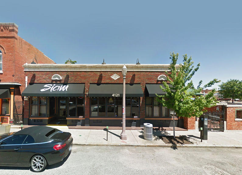 the exterior of a brick building with a black awning and the word siam on it