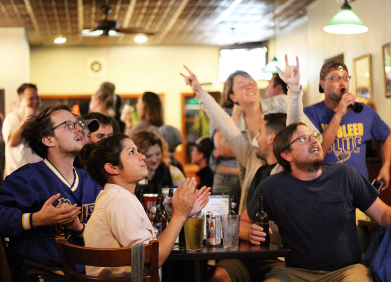 a crowd of st louis blues fans watching a hockey game in a bar