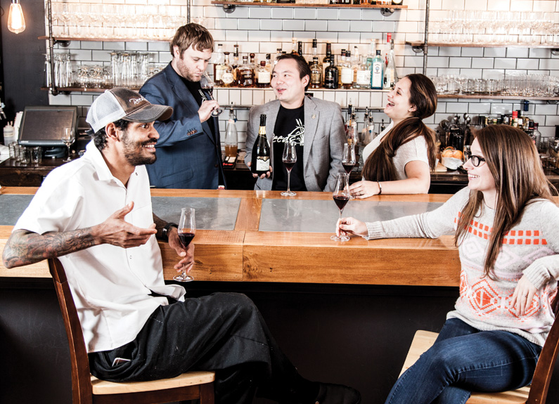 a group of people laughing and sitting at and around a bar