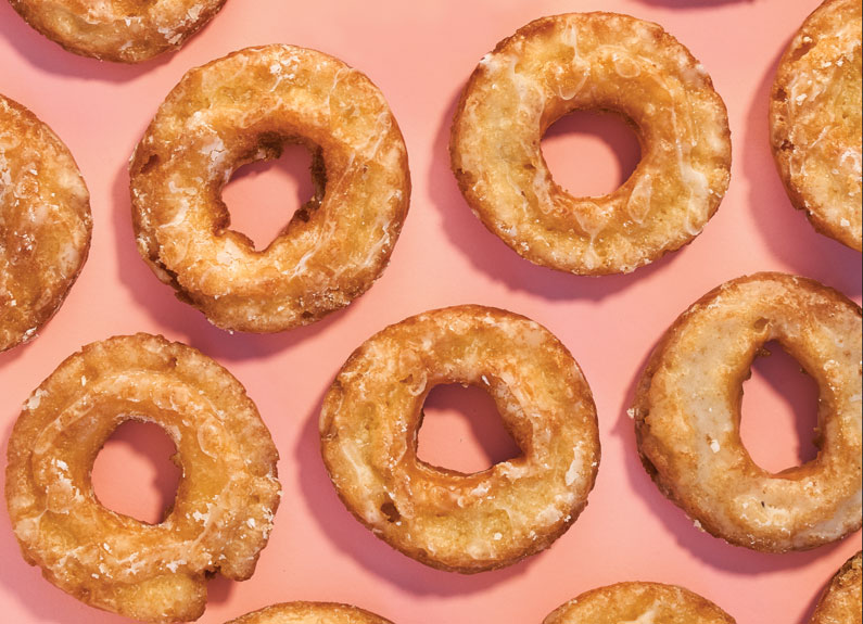 several glazed doughnuts on a pink background