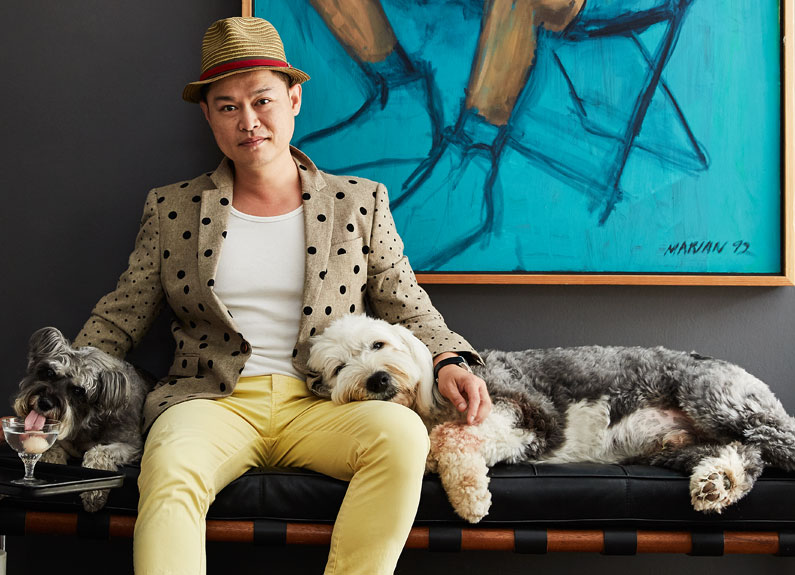 a man sitting on a bench indoors with two dogs