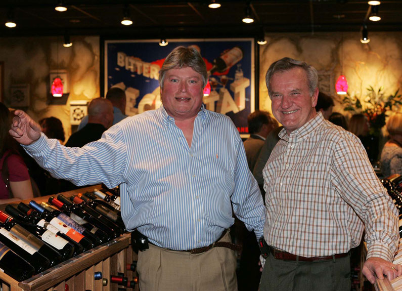 two men with their arms around each other in a dining room