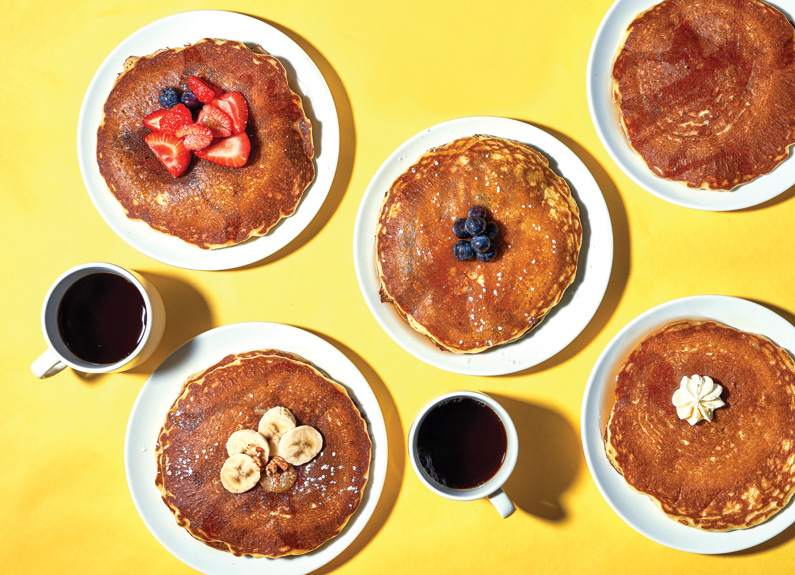 stacks of pancakes and cups of coffee on a yellow background