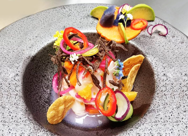 a shallow stone bowl with food topped with colorful garnishes