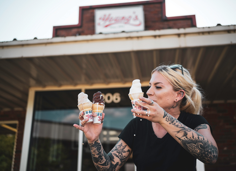 a woman with tattoo sleeves holding melting ice cream cones