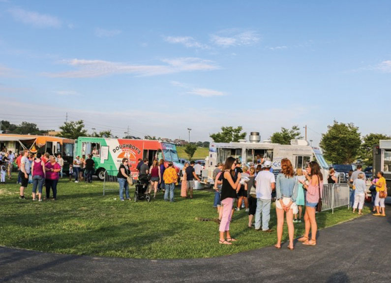 a group of people standing next to food trucks