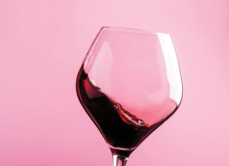 a glass of red wine on a pink background