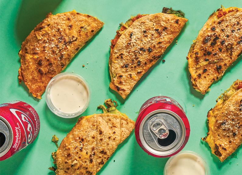 several tacos and soda cans on a green background