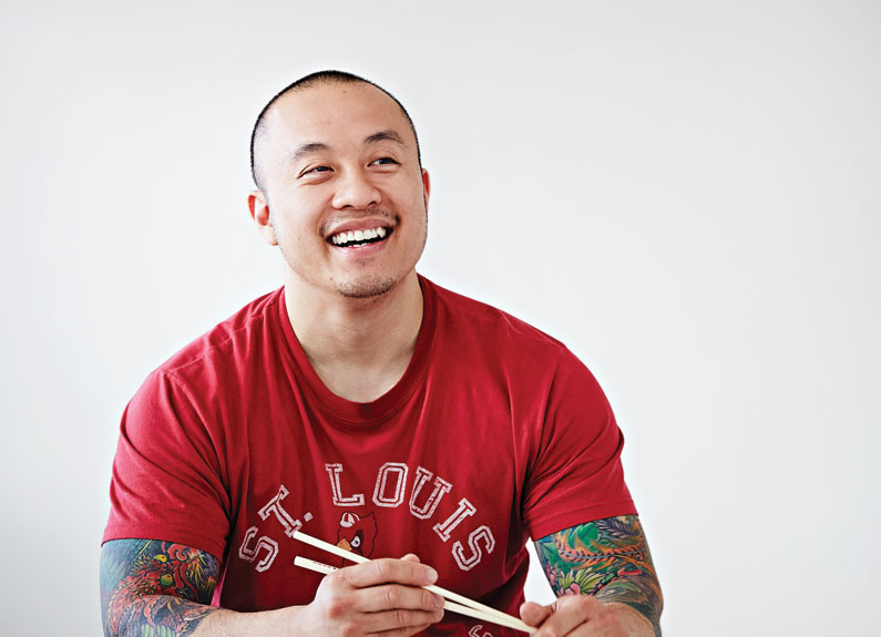 a smiling man in a red shirt with chopsticks