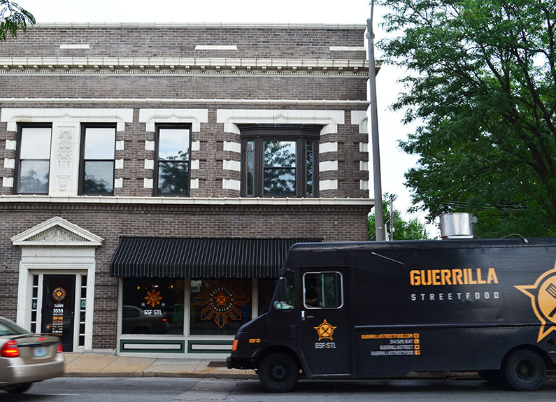 the exterior of a brick building with a food truck in front