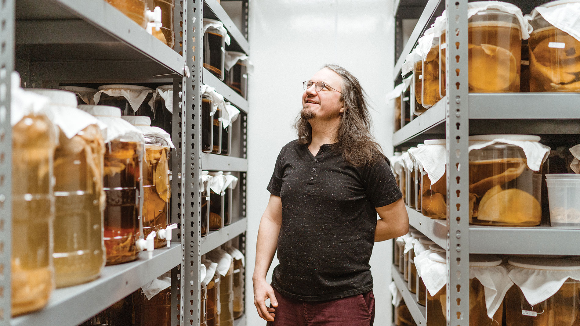 a man walking through shelves of kombucha