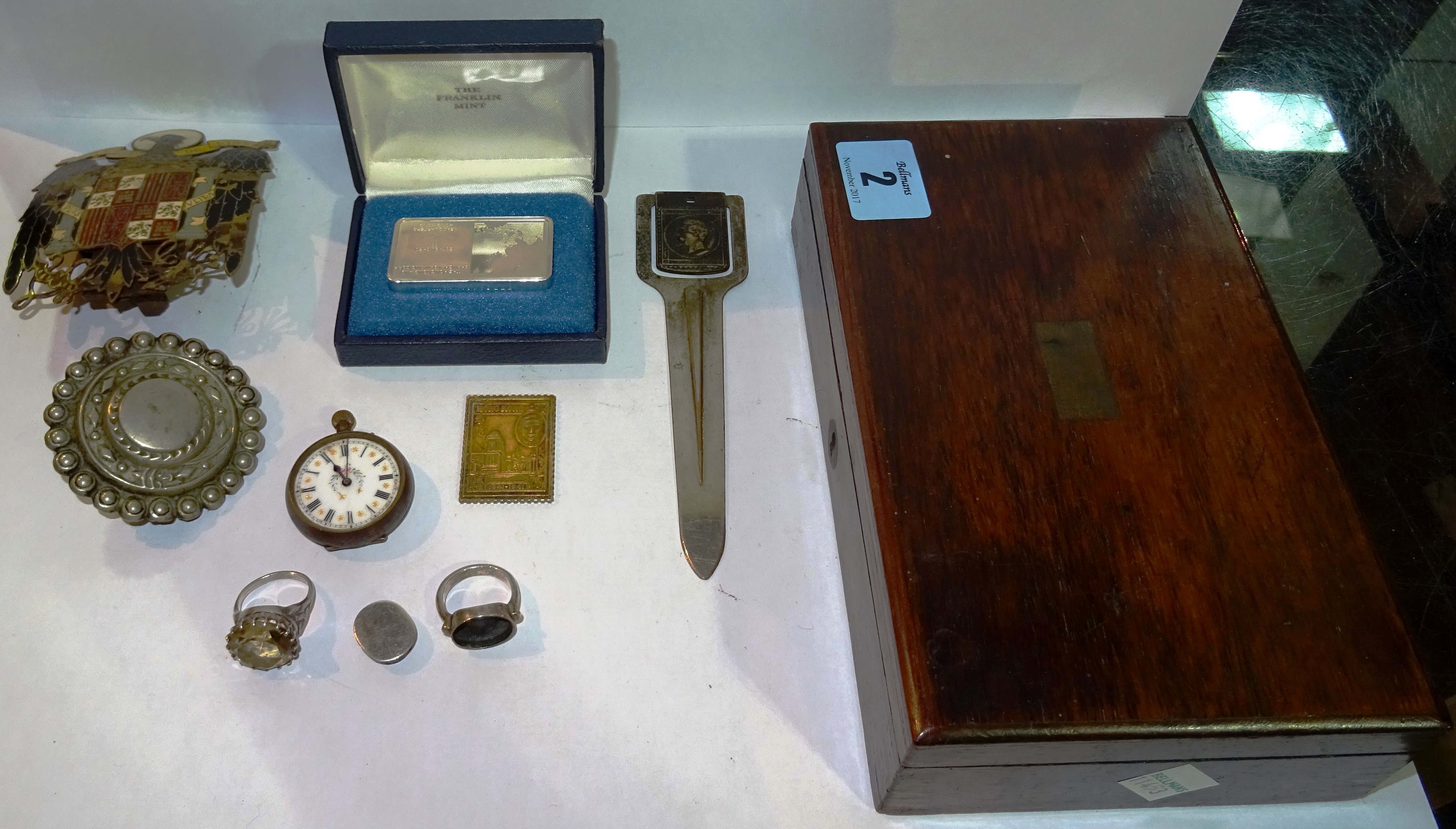 A small quantity of collectables including; a car badge, two silver rings, a 2 ounce silver bar, a poison ring and sundry. CAB