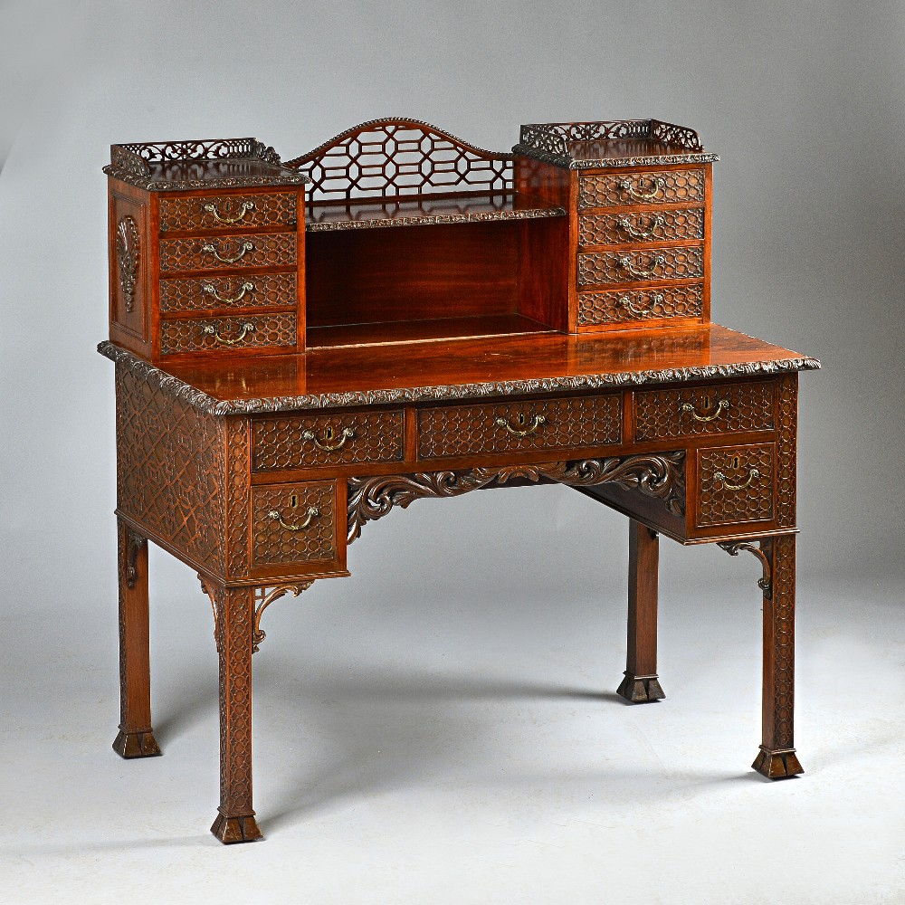 A carved mahogany desk after a design by Chippendale, the whole with blind fretwork decoration, raised back with eight small drawers above three friez