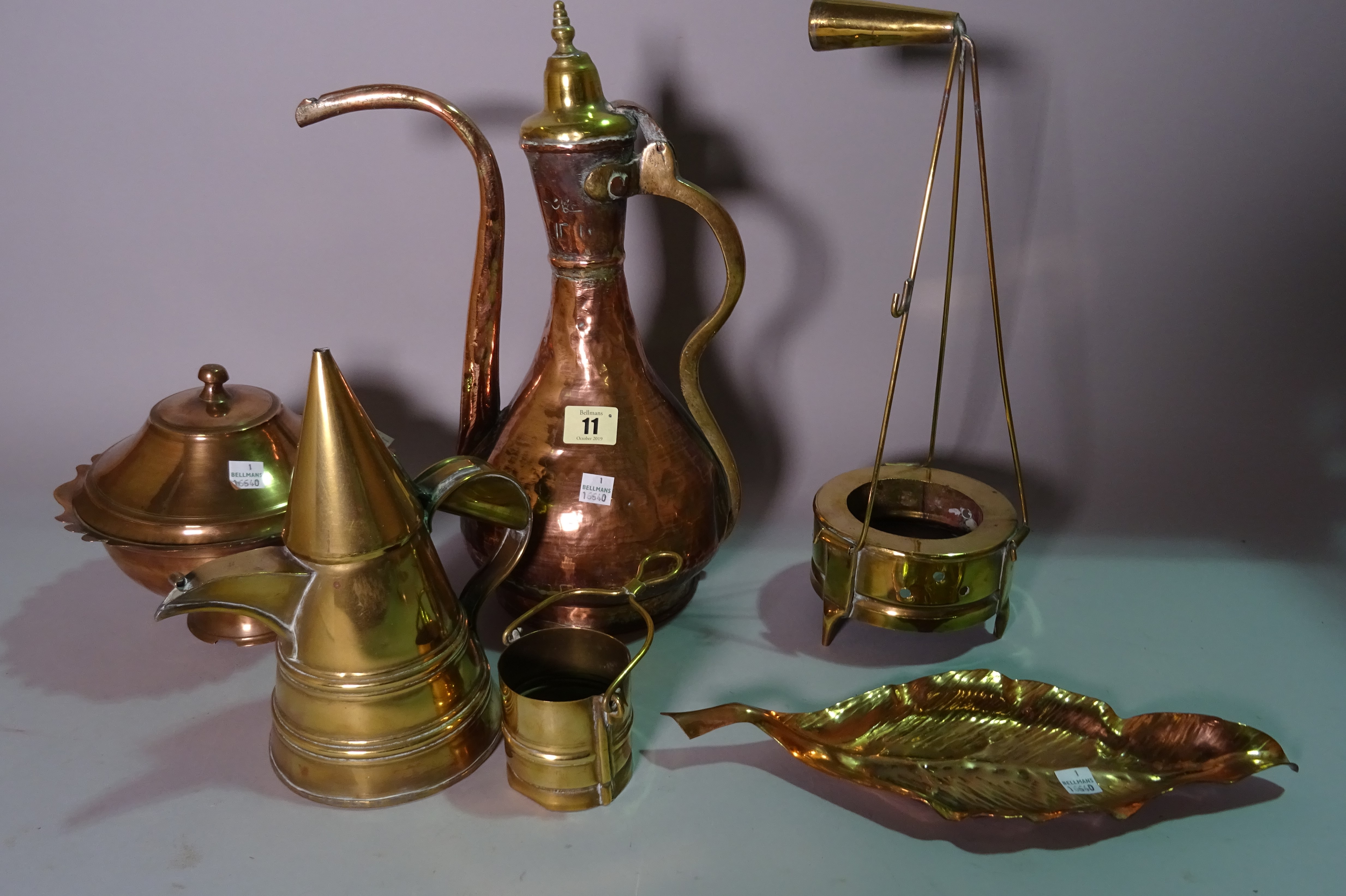 A group of copper and brass including a Turkish ewer, lidded pots, a leaf shaped dish and sundry decorative items.