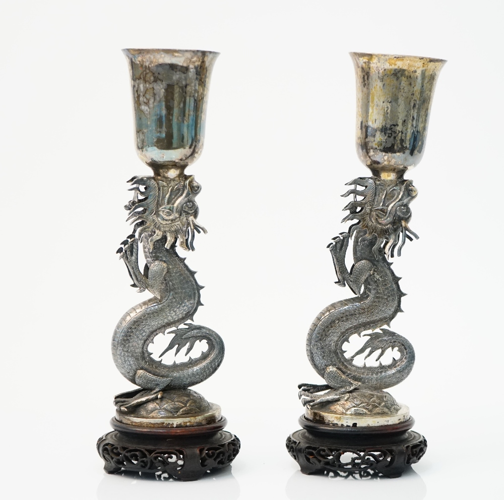 A pair of Chinese vases, each supported by an open mouthed dragon, raised on a circular base, height 24cm, combined weight 693 gms, with a pair of car