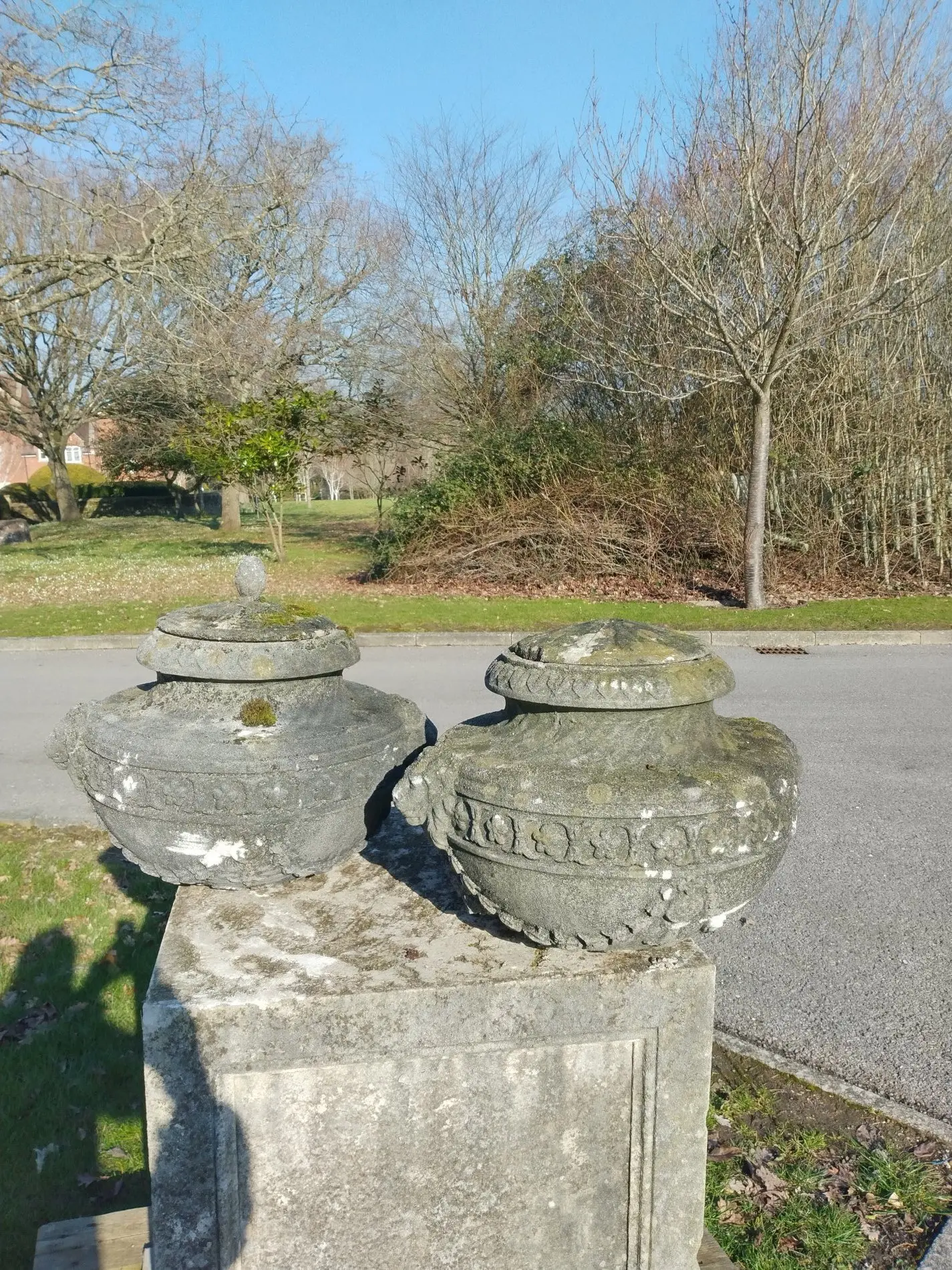 A pair of lidded composition stone urns