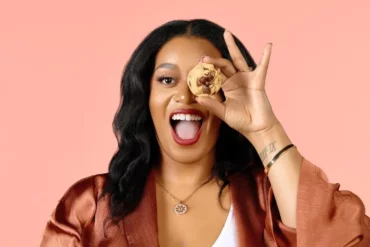 Founder and CEO of Pink Sugar Treats & Eats holding a cookie in front of her left eye