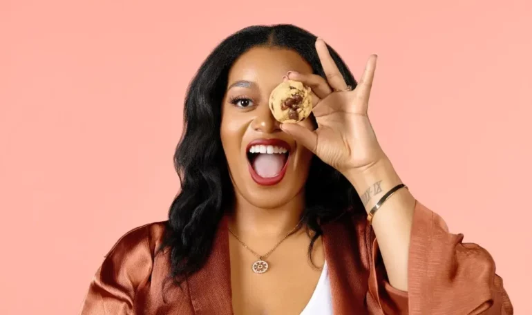 Founder and CEO of Pink Sugar Treats & Eats holding a cookie in front of her left eye