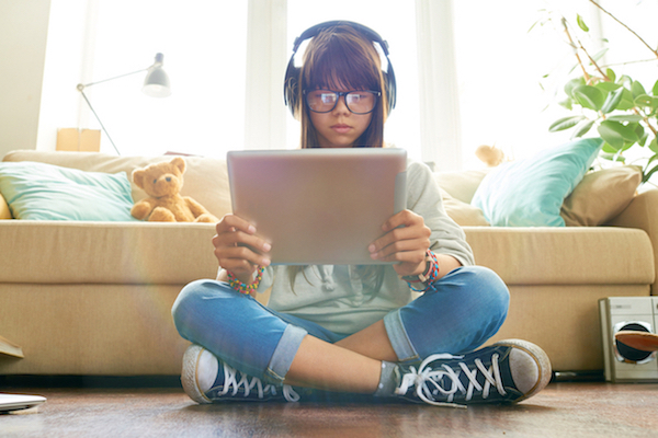 Teenage girl holding digital tablet and looking at screen