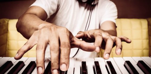 musician hands playing white piano on yellow seat + art filter for music background