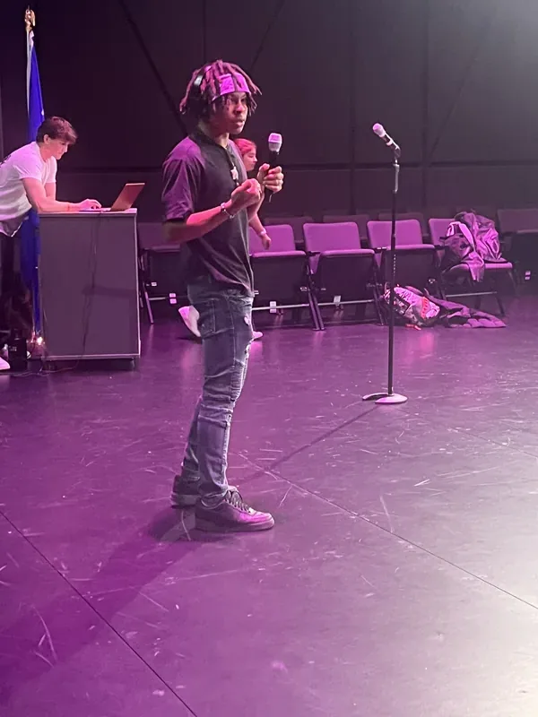 Sun Prairie student performing on stage with microphone at school recording arts showcase