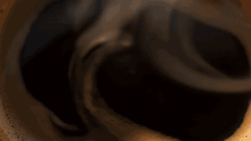AI-generated impossible single continuous shot moving from inside a coffee cup up through a café and out over a city skyline