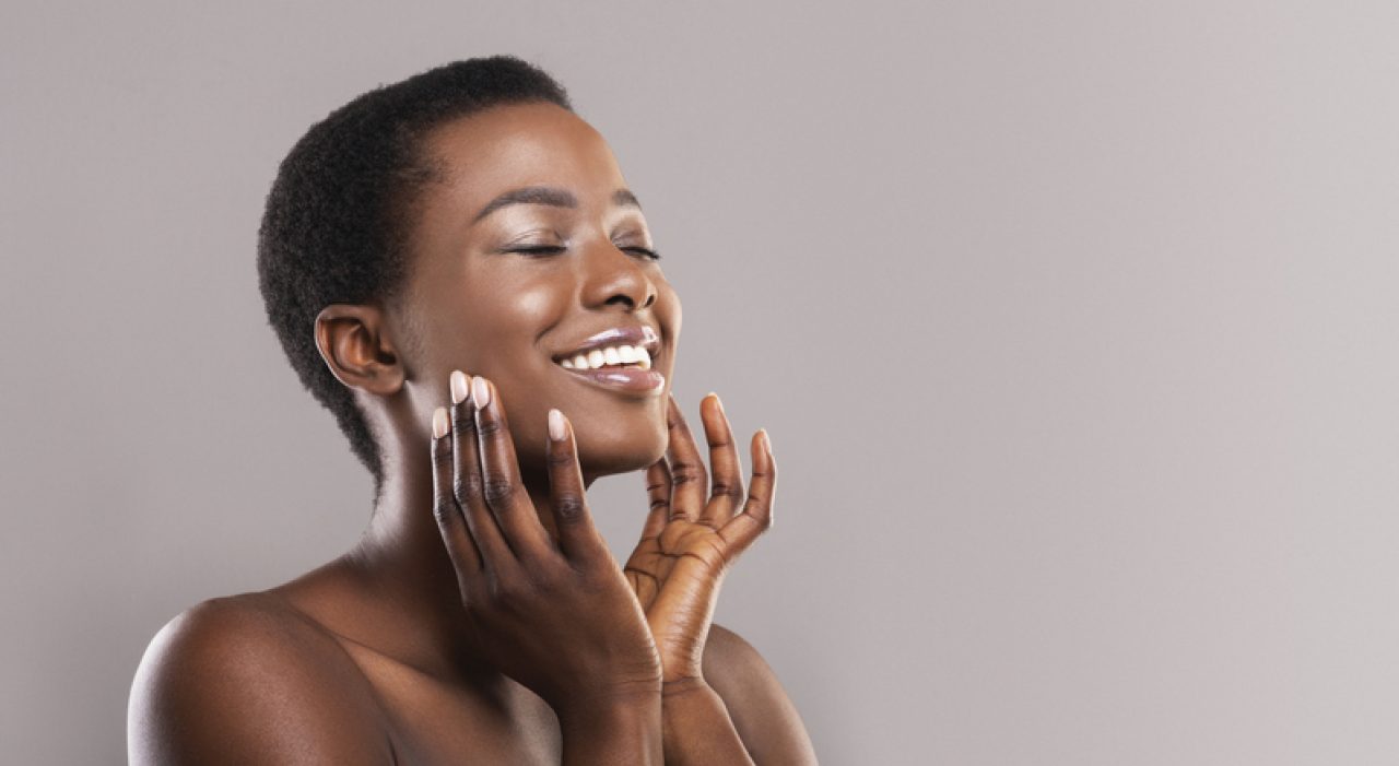 Happy woman touching soft smooth skin on her face to signify the body as sacred