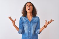 Woman looking up and throwing her arms in the air in anger and frustration