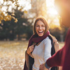 Man and woman reaching for each other's hands in the autumn light.