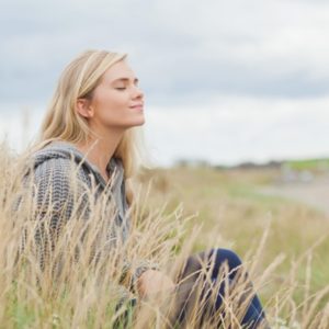 Woman in field thinking of affirmations for peace of mind
