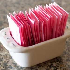 Pink artificial sweetener packets in ceramic dish