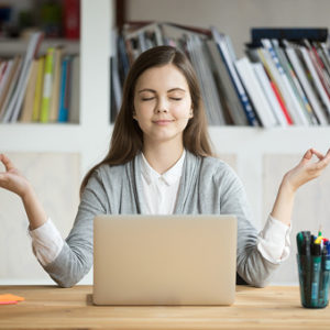 Woman meditating in front of laptop