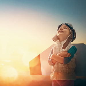 Boy with airplane wings looking up at the sky