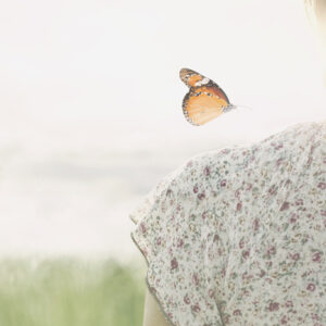 a colorful butterfly about to land delicately on the shoulder of a girl