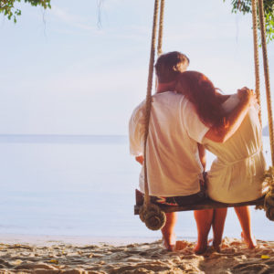 A couple swings on a beach