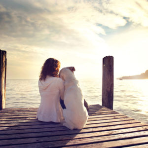 Woman sitting on dock with her dog