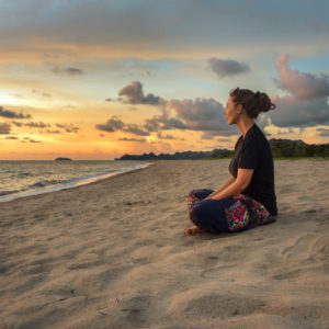 Woman sitting on beach at sunset