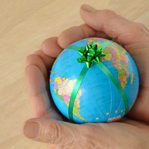 Woman hands holding a small earth with a green ribbon