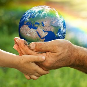 Elderly and child's hands holding the earth with a rainbow.