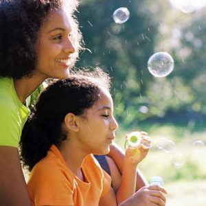 Woman blowing bubbles with daughter