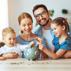 Mom and dad showing kids how to manage money with a piggybank